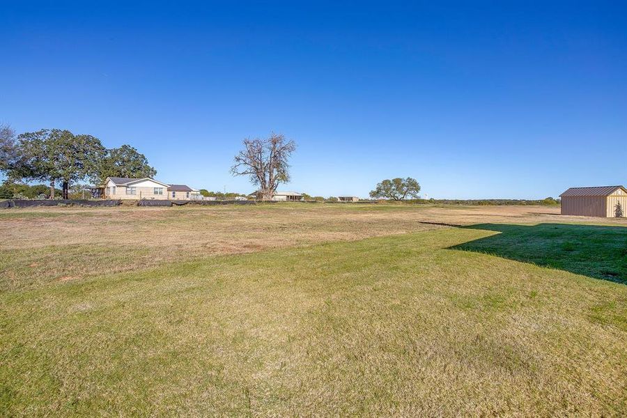 View of green lawn with a view of countryside and an outbuilding