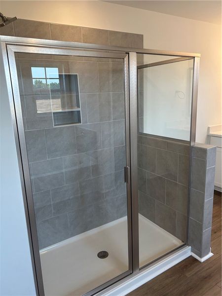 A sleek, tiled shower with glass enclosure offers