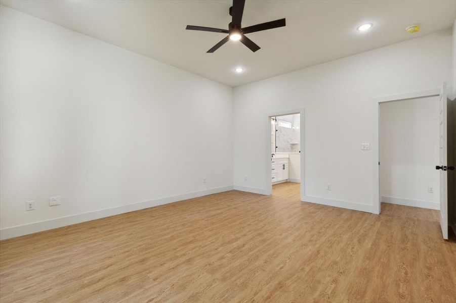 Unfurnished bedroom featuring ensuite bath, light wood-type flooring, and ceiling fan