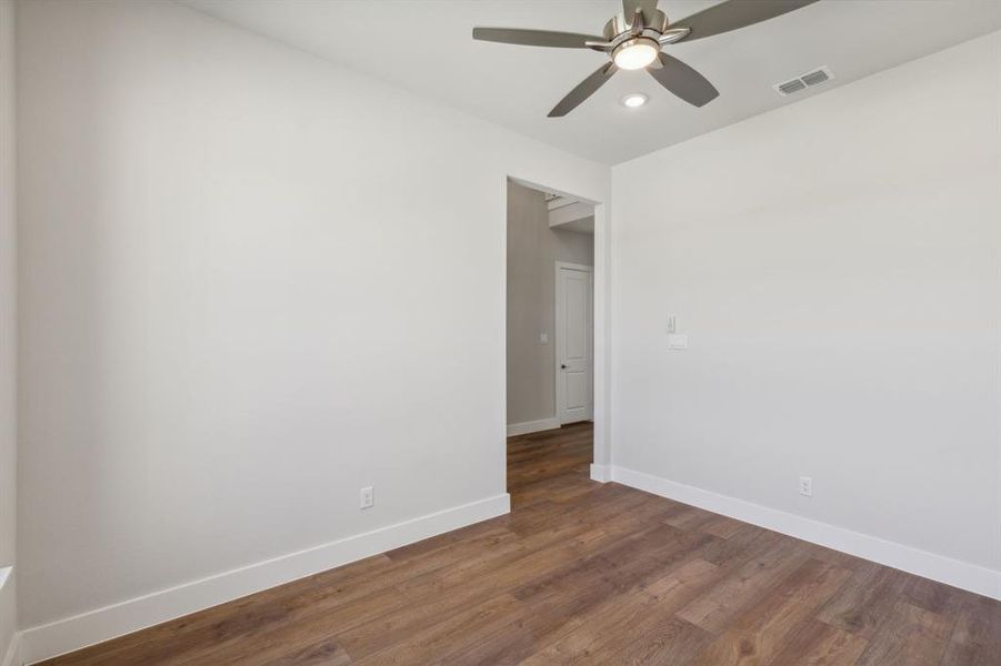 Unfurnished room featuring dark wood-type flooring and ceiling fan