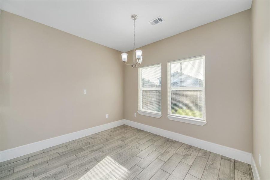 Empty room with a chandelier and light hardwood / wood-style floors