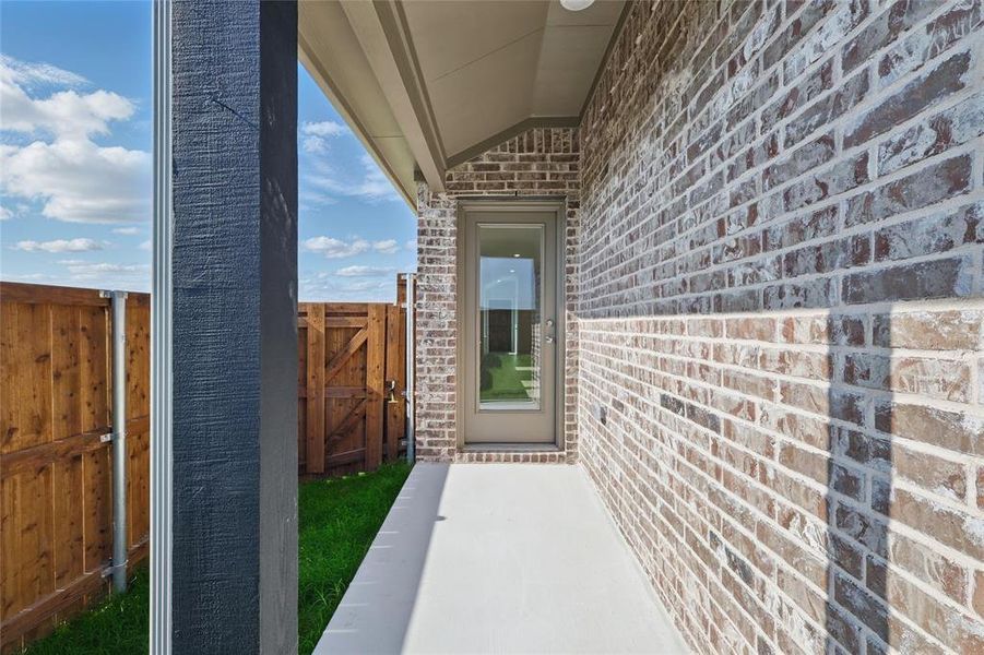 Doorway to property featuring brick siding and a gate