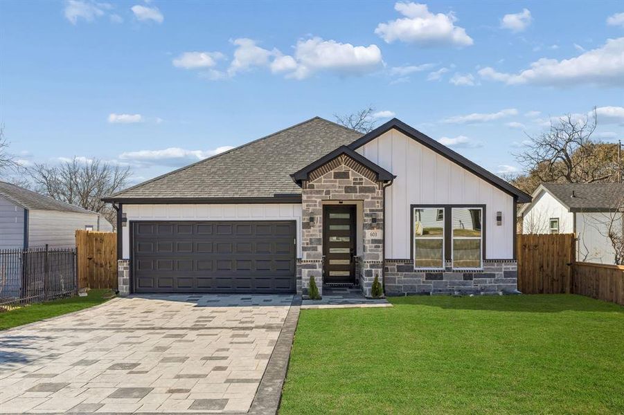 View of front of house with stone siding, driveway, board and batten siding, a shingled roof, and an attached garage