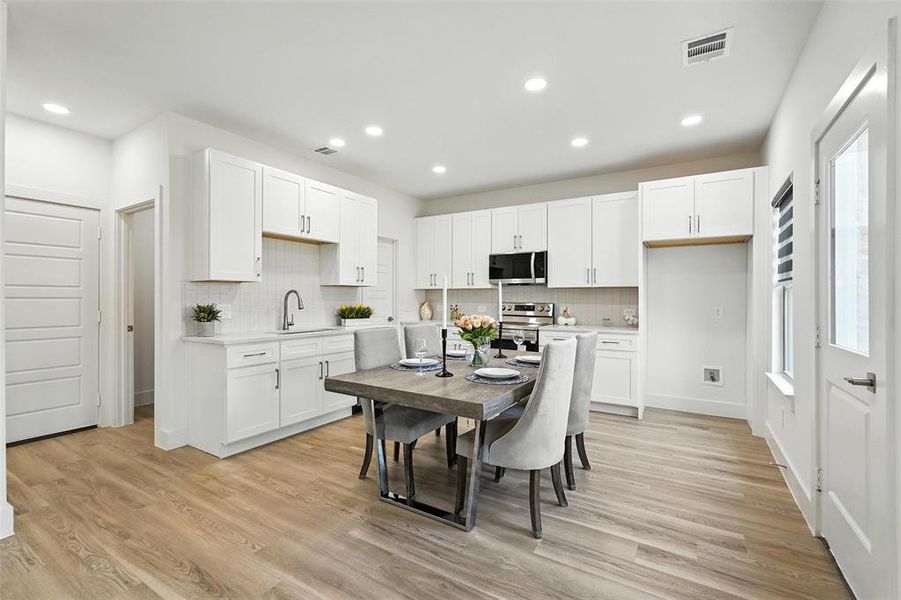 Kitchen featuring white cabinets, backsplash, light wood finished floors, and recessed lighting