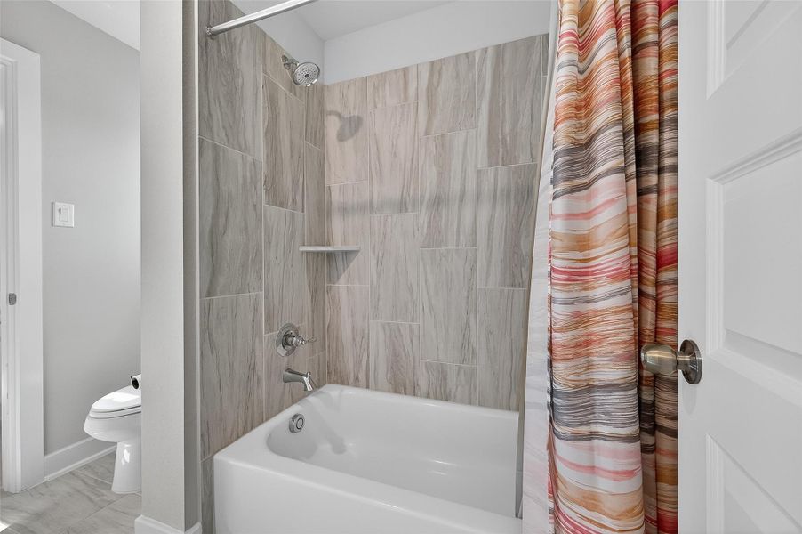 This full bathroom features a combination of neutral tile and smooth bathroom appliances. The deep soaking tub is perfect for relaxing after a long day.