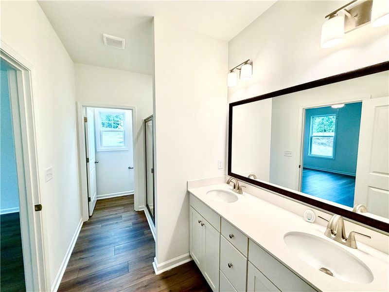 A spacious double vanity and rich wood floors anch
