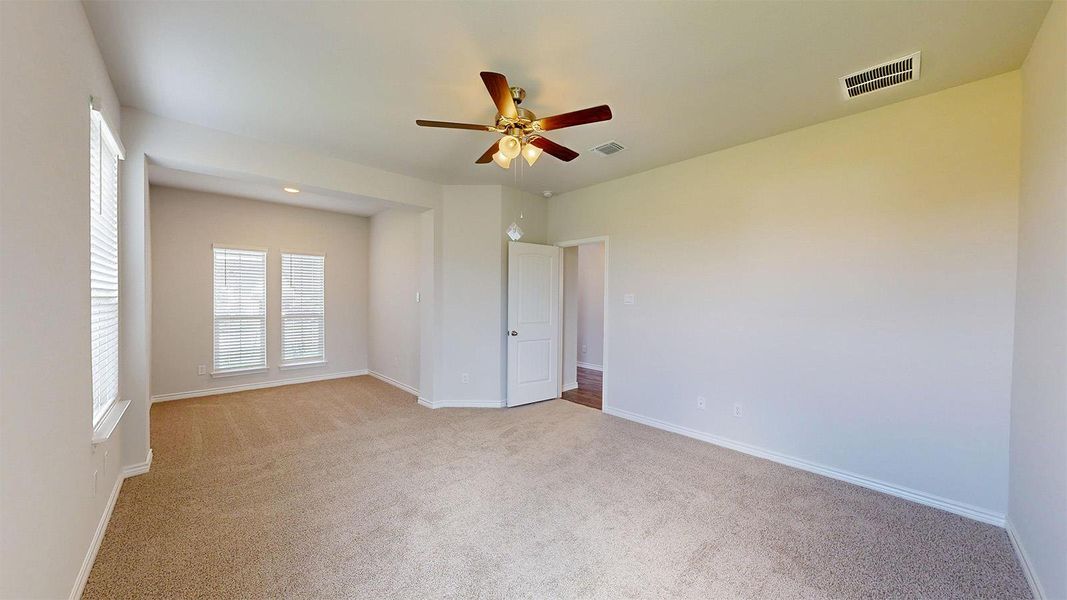 Spacious room featuring neutral carpet, light-colored walls, and a ceiling fan