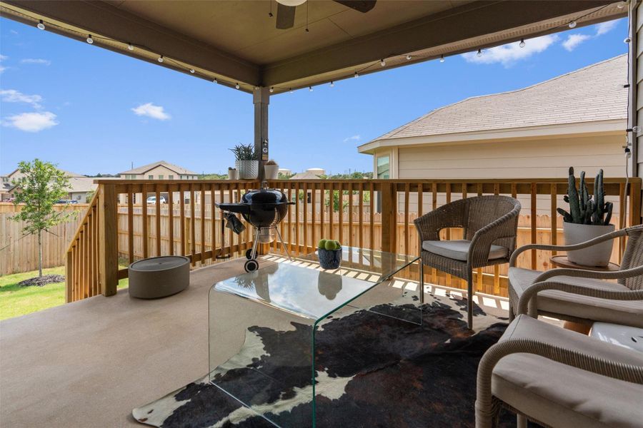 Spacious covered patio featuring a concrete surface, wooden railings, and string lights Spacious covered patio featuring a concrete surface, wooden railings, and string lights