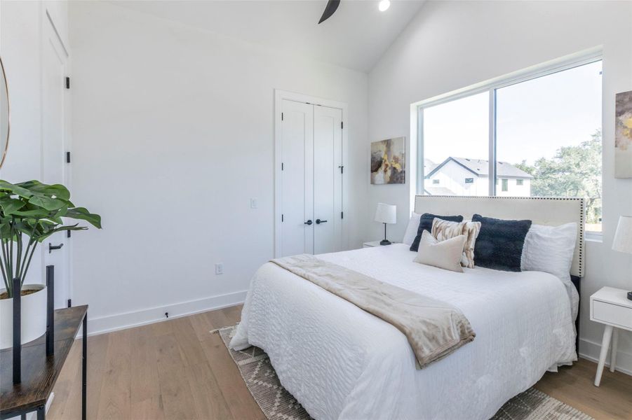 Bedroom featuring light wood-style flooring, a closet, vaulted ceiling, and a ceiling fan