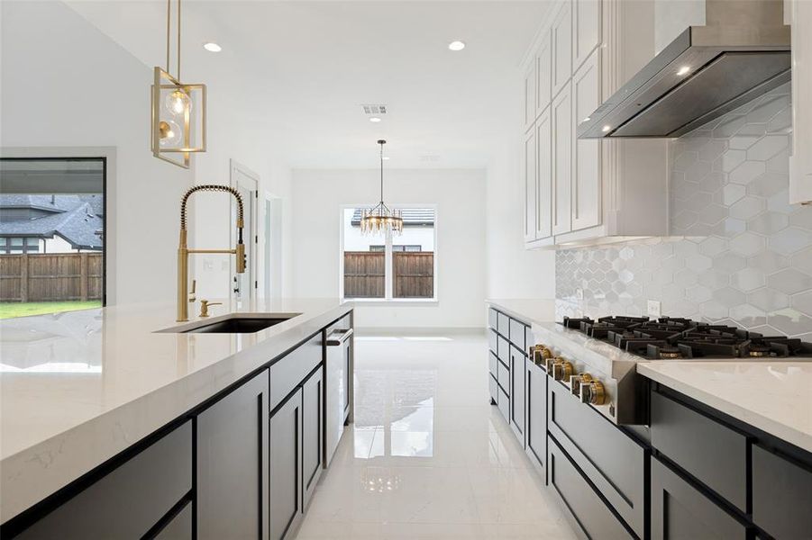Modern kitchen featuring a gas range with stainless steel hood, white shaker-style upper cabinetry, and dark lower cabinetry Modern kitchen featuring a gas range with stainless steel hood, white shaker-style upper cabinetry, and dark lower cabinetry