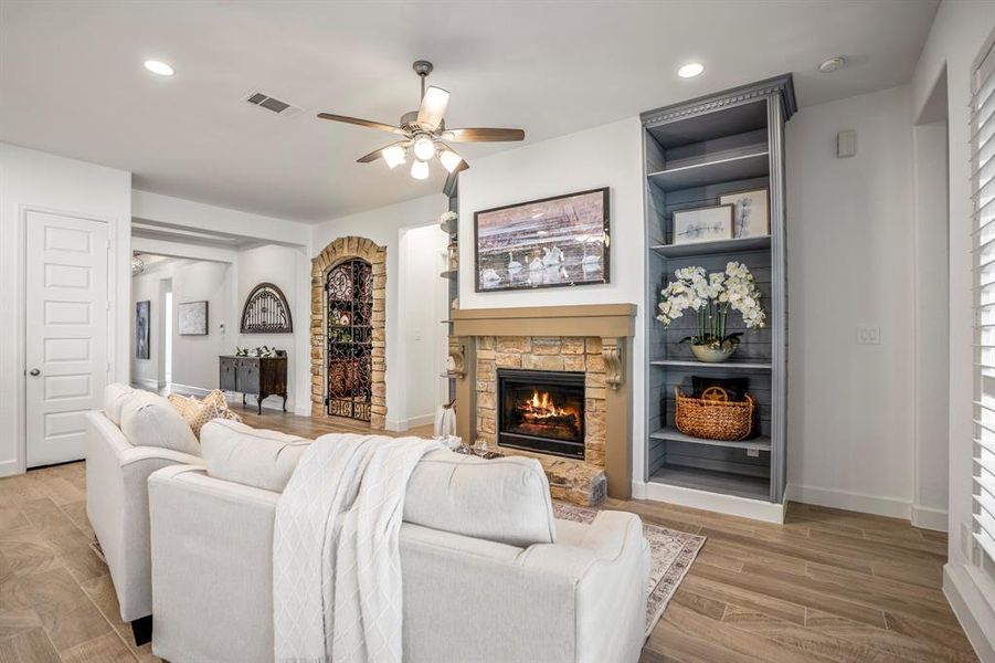 The living room features a cozy stone fireplace with built-in shelving on both sides, adorned with decorative items and plants.