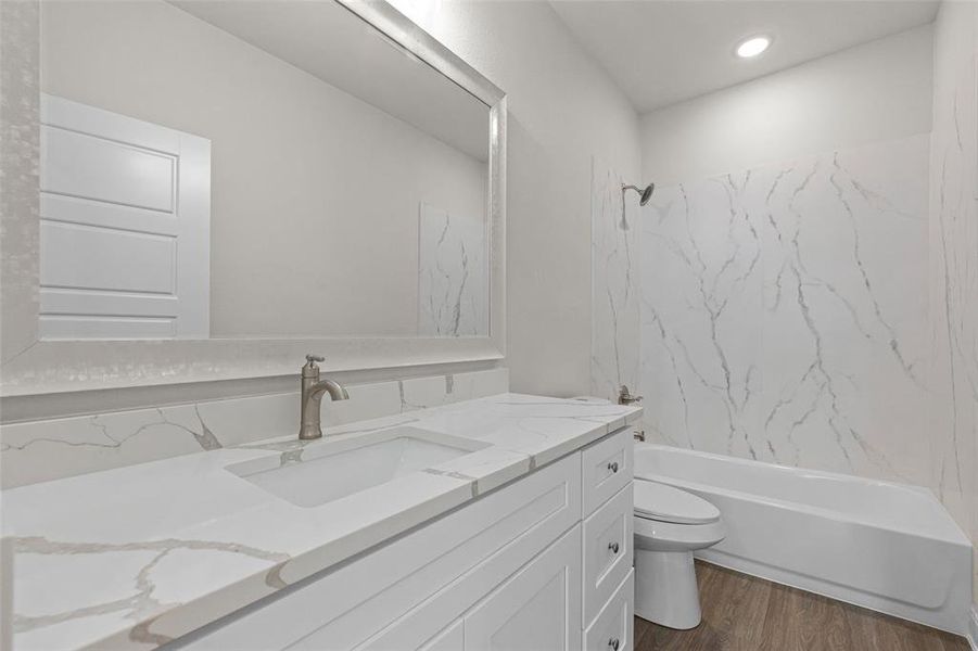 Full bathroom with tiled shower / bath combo, vanity, toilet, and hardwood / wood-style floors