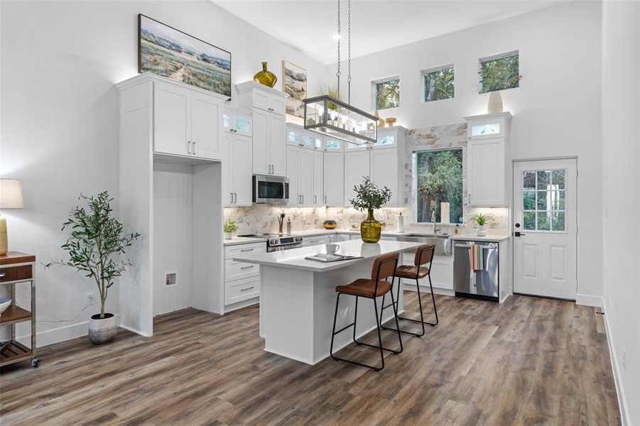 Kitchen featuring plenty of natural light, a center island, appliances with stainless steel finishes, and white cabinetry