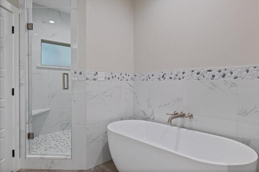 Bathroom featuring separate shower and tub and tile walls