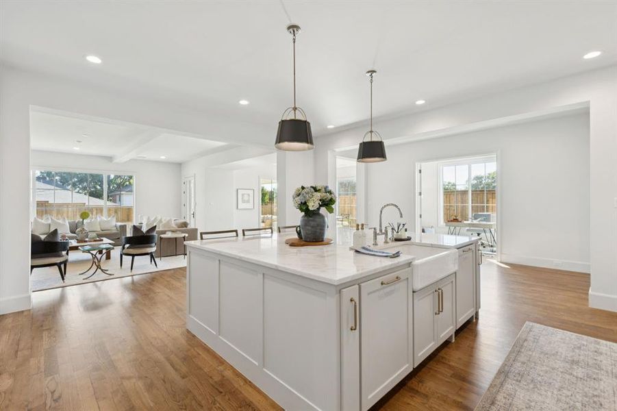 Kitchen with recessed lighting, open floor plan, light stone countertops, hanging light fixtures, and light wood-type flooring Kitchen with recessed lighting, open floor plan, light stone countertops, hanging light fixtures, and light wood-type flooring