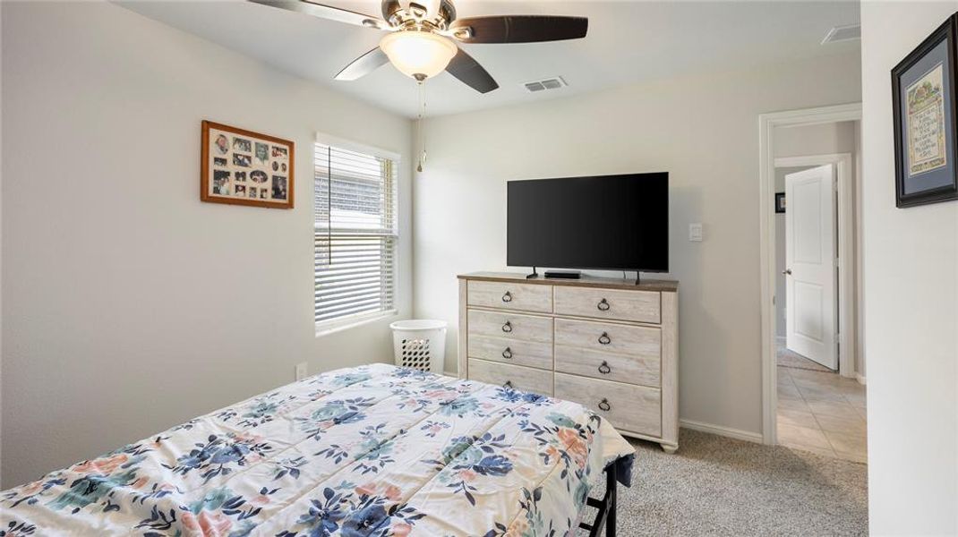 Bedroom with light colored carpet and a ceiling fan