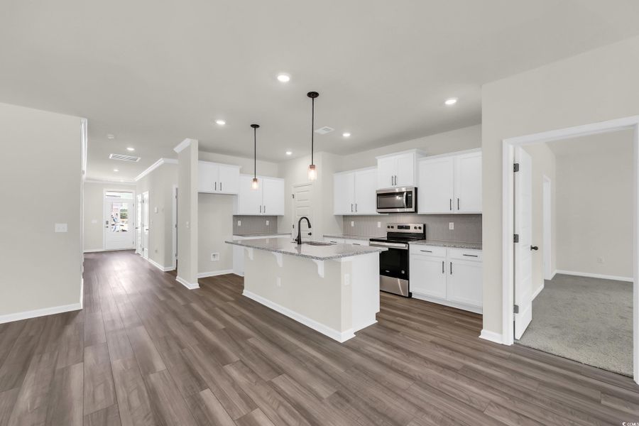 Kitchen with backsplash, stainless steel appliances, pendant lighting, white cabinets, and recessed lighting