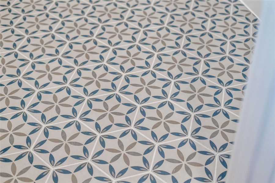 The photo highlights the stylish and durable tile flooring in the laundry room. This choice adds a touch of personality and flair to the space with its repeating geometric design forming a star or floral motif.