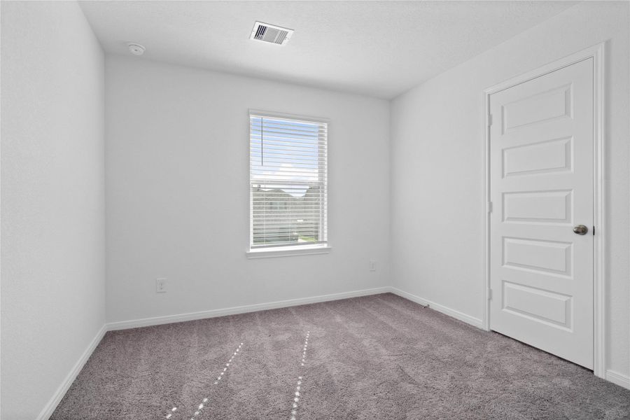This secondary bedroom offers comfort and style with plush carpeting, neutral paint tones, recessed lighting, large window with blinds, and a walk-in closet.
