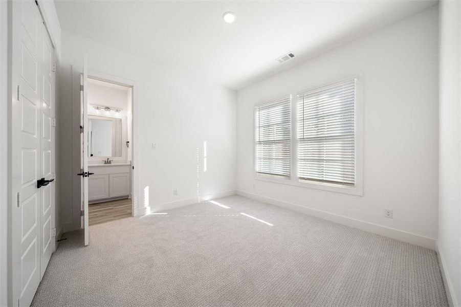 Unfurnished bedroom with light carpet, a closet, connected bathroom, and recessed lighting