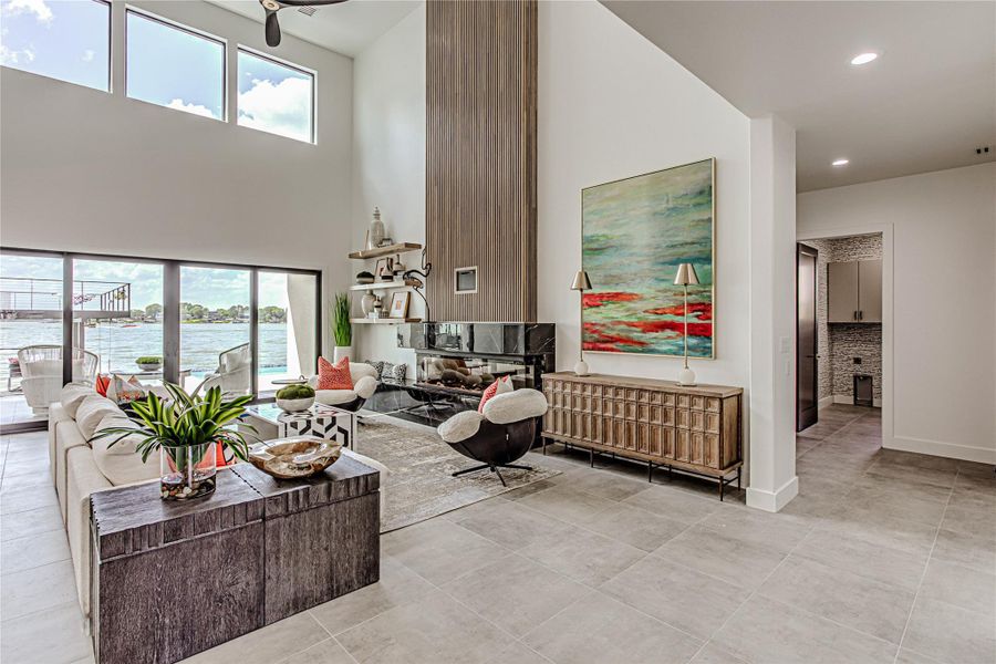 Living room with a towering ceiling, plenty of natural light, recessed lighting, a water view, and light tile patterned flooring