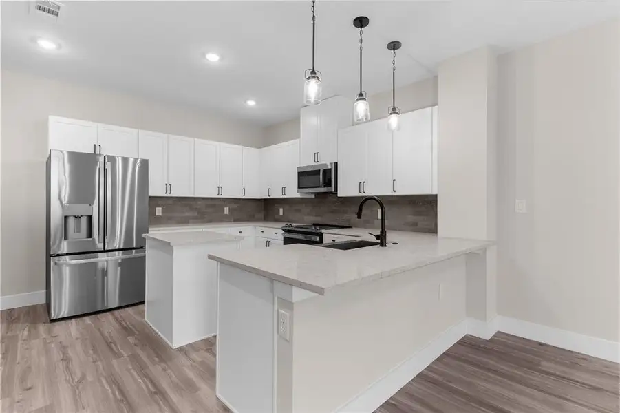 Modern kitchen featuring white cabinetry, stainless steel appliances, and a light-toned countertop