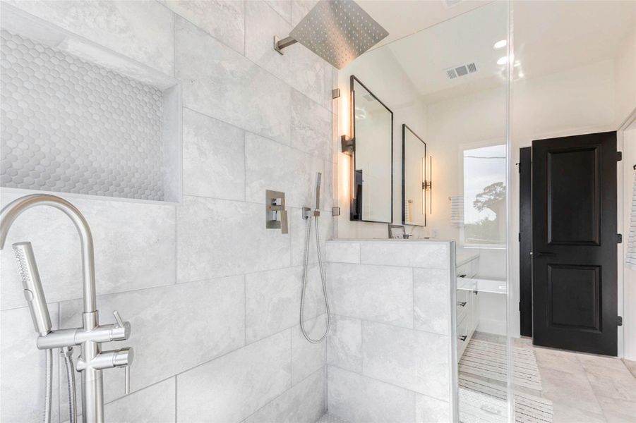 The walk-in shower features a rainfall showerhead, integrated wall niche, and sleek glass partitioning.