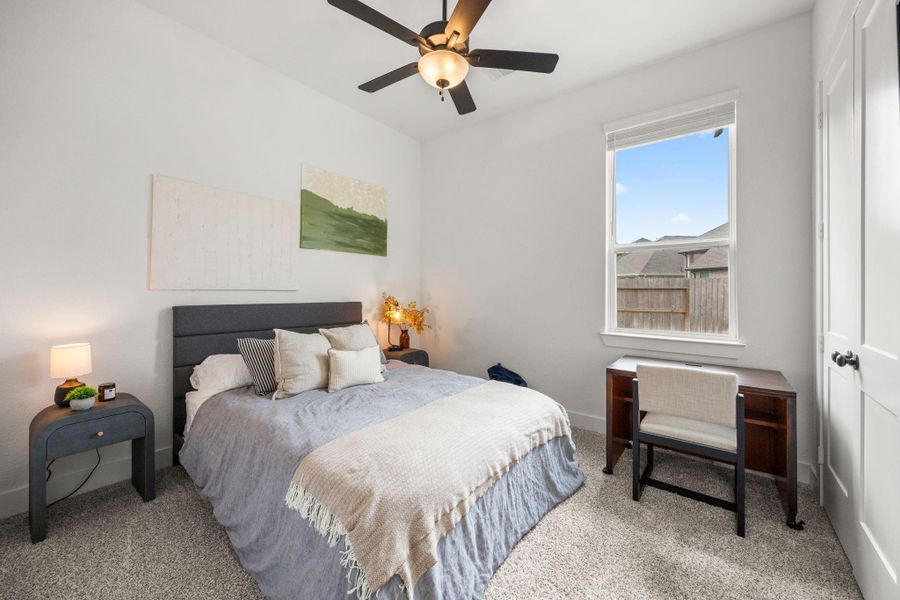 Neutral tones, carpeted flooring, and a ceiling fan create a comfortable guest or secondary bedroom setup.
