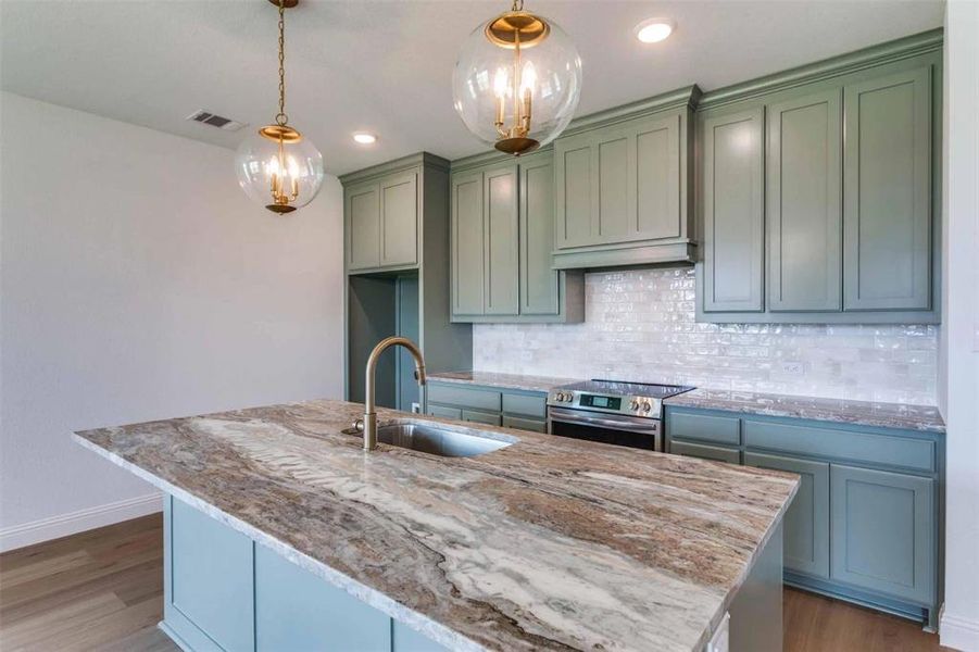 Kitchen with stainless steel range with electric stovetop, decorative backsplash, light stone countertops, dark wood finished floors, and recessed lighting Kitchen with stainless steel range with electric stovetop, decorative backsplash, light stone countertops, dark wood finished floors, and recessed lighting