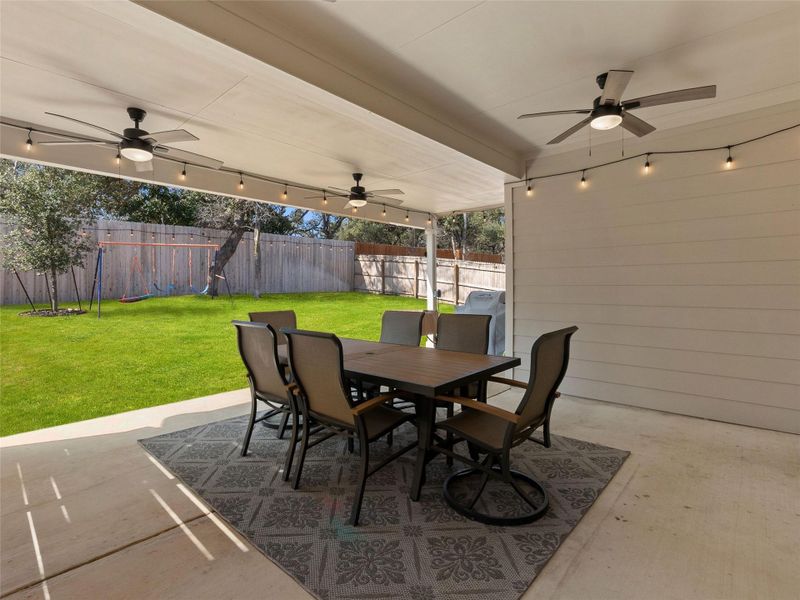 Fenced backyard featuring ceiling fan, a patio, and outdoor dining area
