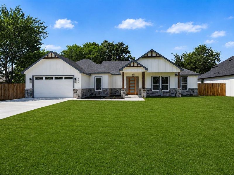 Modern farmhouse exterior featuring white vertical siding, stone accents, dark trim, a prominent wooden entry door, and an attached two-car garage Modern farmhouse exterior featuring white vertical siding, stone accents, dark trim, a prominent wooden entry door, and an attached two-car garage