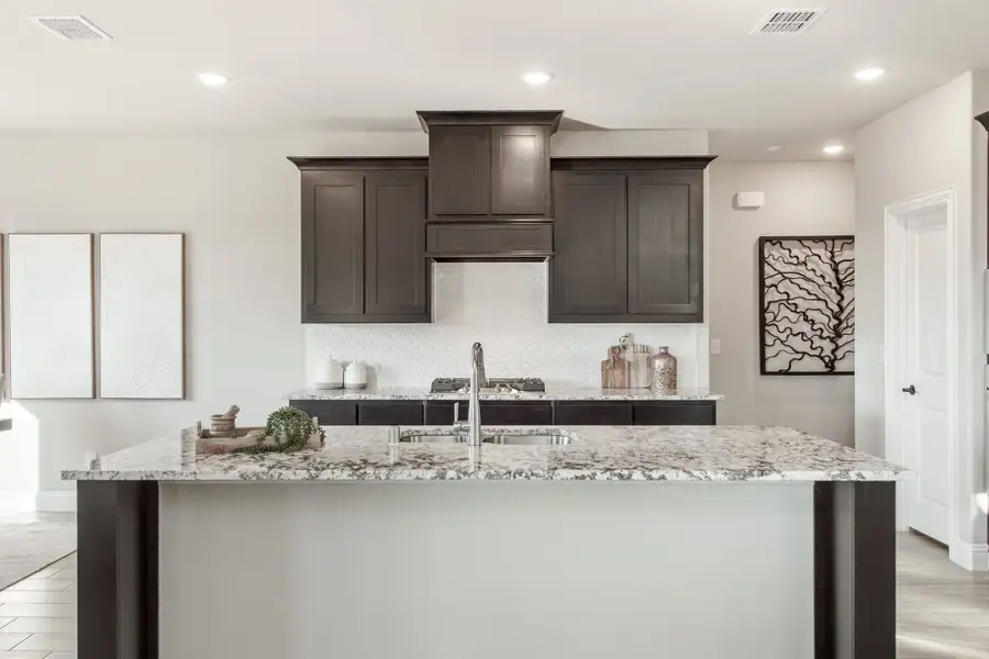 Kitchen with large granite island, dark wood cabinets, and built-in range hood Kitchen with large granite island, dark wood cabinets, and built-in range hood