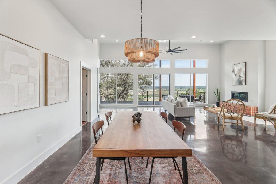 Dining area featuring finished concrete flooring, baseboards, a ceiling fan, recessed lighting, and a high ceiling Dining area featuring finished concrete flooring, baseboards, a ceiling fan, recessed lighting, and a high ceiling