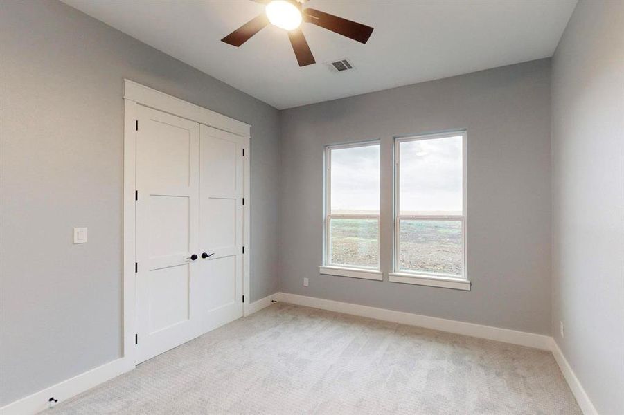 Unfurnished bedroom featuring ceiling fan, light carpet, and a closet