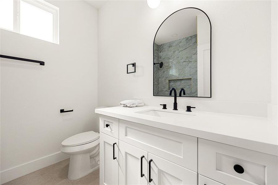 This beautifully designed bathroom features a sleek vanity with quartz countertops, black fixtures, and modern lighting. The neutral tones and stylish finishes create a clean and sophisticated space, perfect for guests or everyday use!