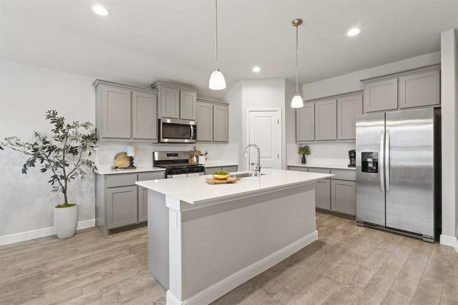 Contemporary kitchen featuring a center island with a sink, light gray cabinetry, stainless steel appliances, wood-finish flooring, and recessed lighting Contemporary kitchen featuring a center island with a sink, light gray cabinetry, stainless steel appliances, wood-finish flooring, and recessed lighting