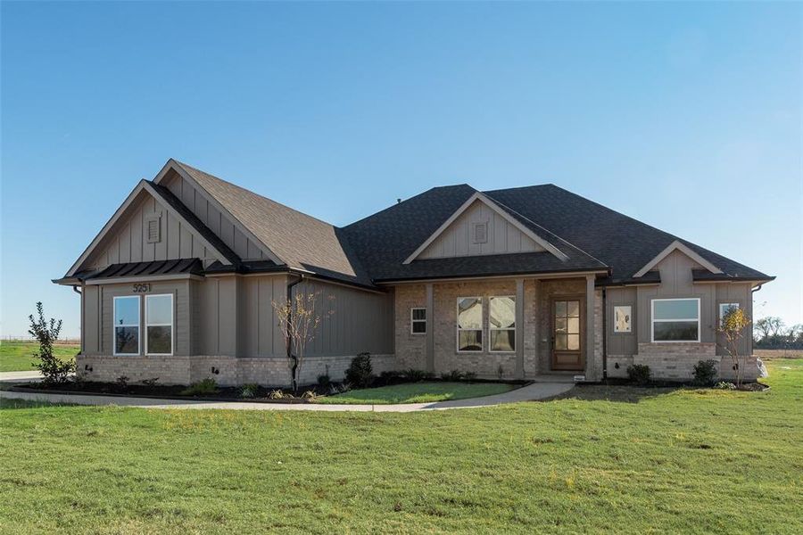 Modern farmhouse featuring a front lawn, brick siding, and board and batten siding Modern farmhouse featuring a front lawn, brick siding, and board and batten siding