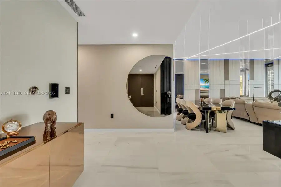 Large-format light-toned flooring, circular interior wall cutout, linear ceiling lighting, and integrated wall paneling Large-format light-toned flooring, circular interior wall cutout, linear ceiling lighting, and integrated wall paneling