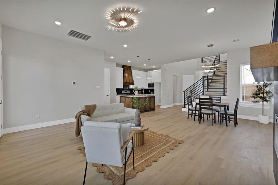 Living room featuring stairs, baseboards, light wood-type flooring, recessed lighting, and a chandelier Living room featuring stairs, baseboards, light wood-type flooring, recessed lighting, and a chandelier