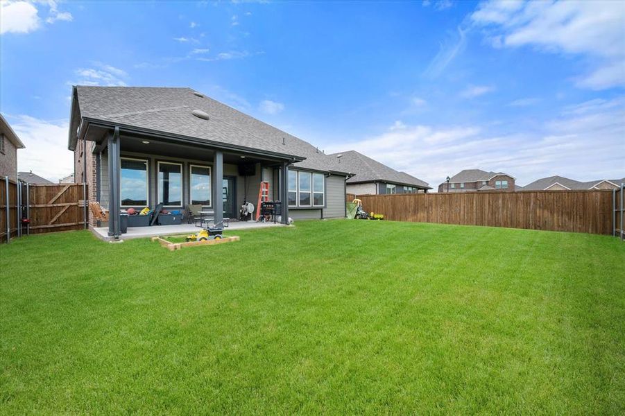 Expansive backyard featuring a covered patio, a large grass lawn, and wood privacy fencing