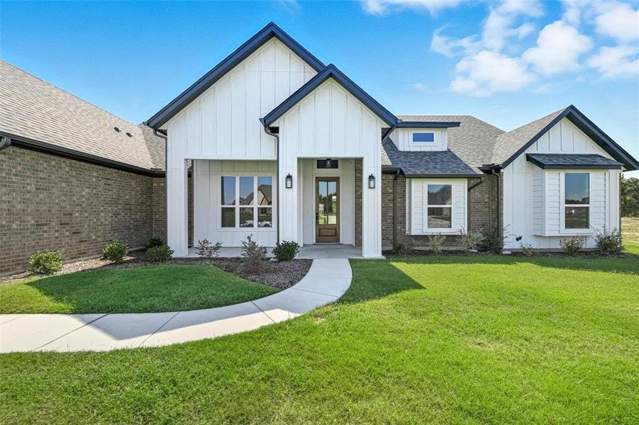 Modern farmhouse featuring roof with shingles, board and batten siding, and a front lawn Modern farmhouse featuring roof with shingles, board and batten siding, and a front lawn