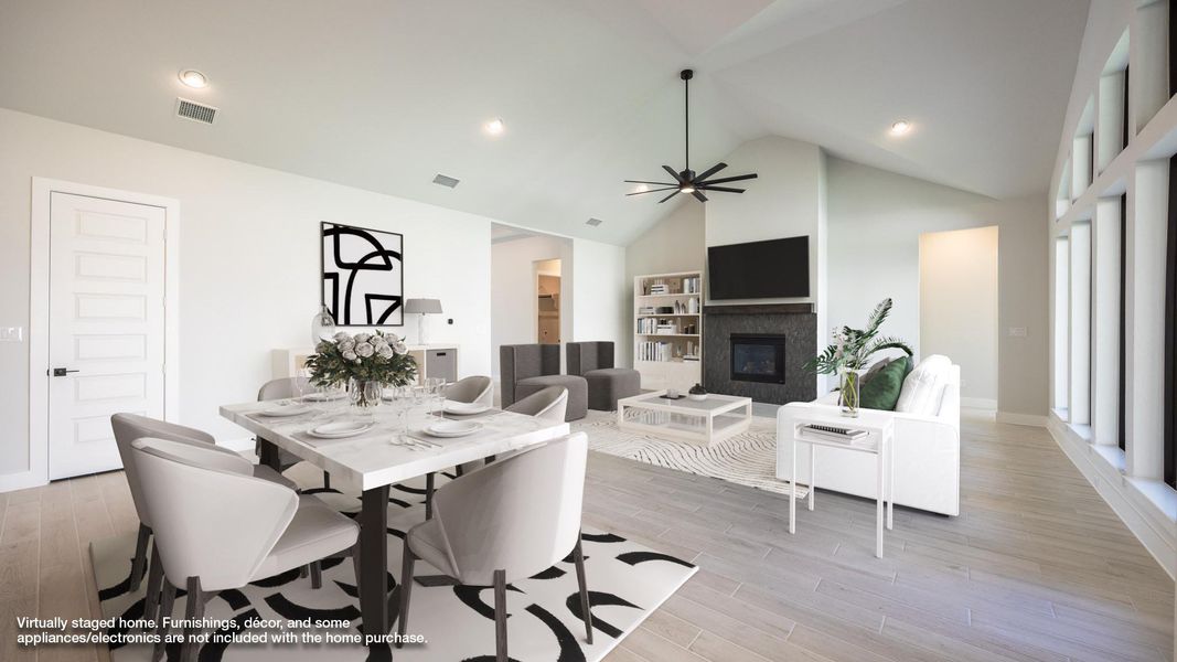 Dining area featuring a glass covered fireplace, light wood-style flooring, recessed lighting, high vaulted ceiling, and a ceiling fan