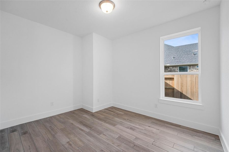 The first floor secondary bedroom with ensuite bathroom is perfect for guests or family who need to be close to the main living area. It features wood-look tile flooring, large window, neutral toned walls, and an ample sized closet.