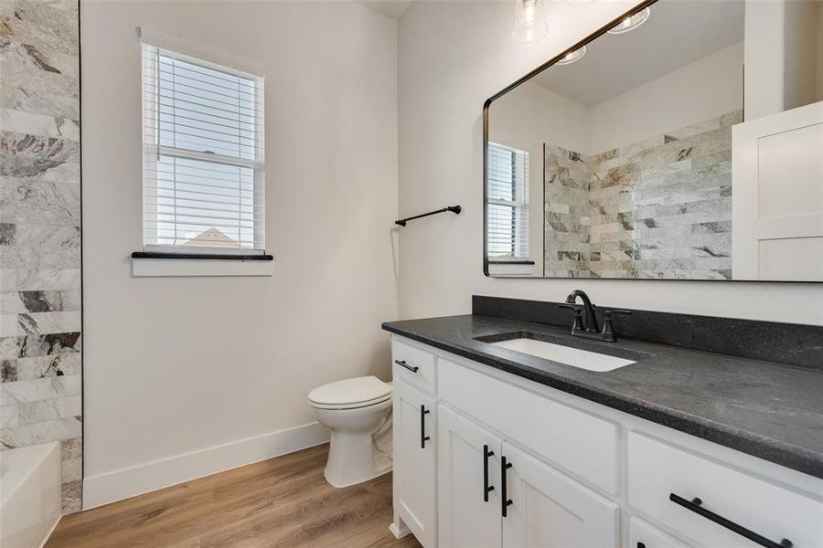 Full bathroom featuring hardwood / wood-style floors, vanity, toilet, and tiled shower / bath