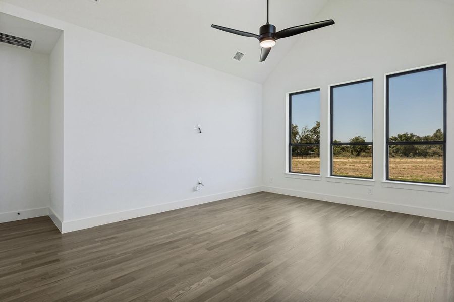 High vaulted ceilings and wood floors frame large windows overlooking the natural landscape.