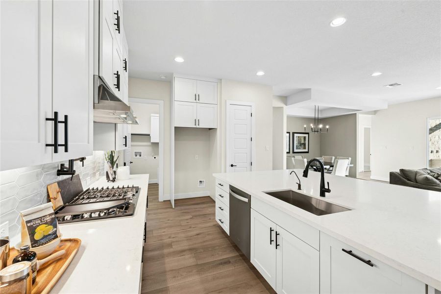 Kitchen with light stone countertops, white cabinets, light wood-style flooring, recessed lighting, and open floor plan Kitchen with light stone countertops, white cabinets, light wood-style flooring, recessed lighting, and open floor plan