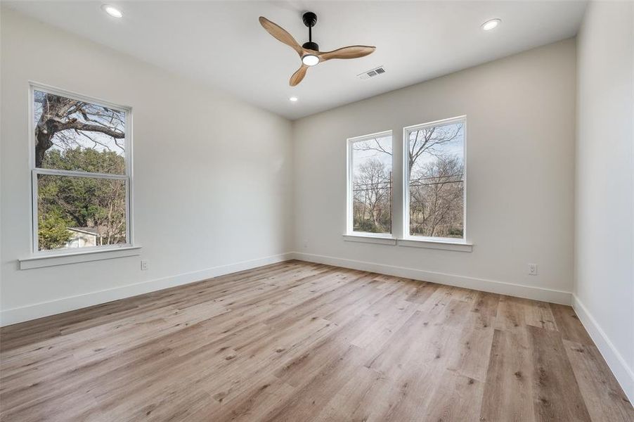 Empty room with light wood finished floors, a ceiling fan, plenty of natural light, and recessed lighting
