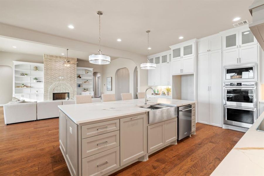 Kitchen with sink, decorative light fixtures, white cabinetry, and dark wood-type flooring