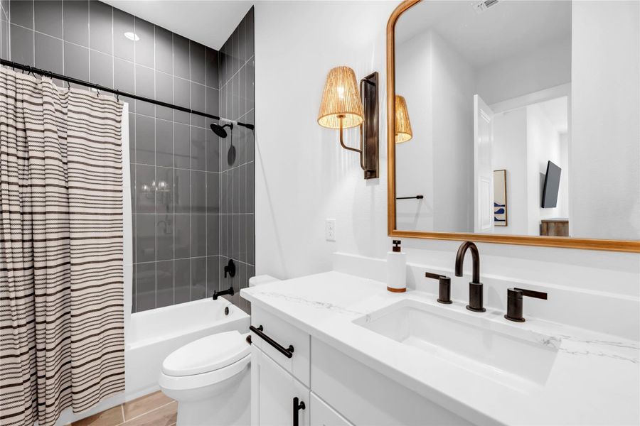 Bathroom six: A modern bathroom displays a sleek quartz vanity paired with vertical dark tiling.