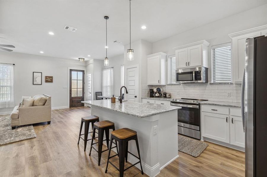 Kitchen featuring white cabinets, appliances with stainless steel finishes, light wood-type flooring, and plenty of natural light